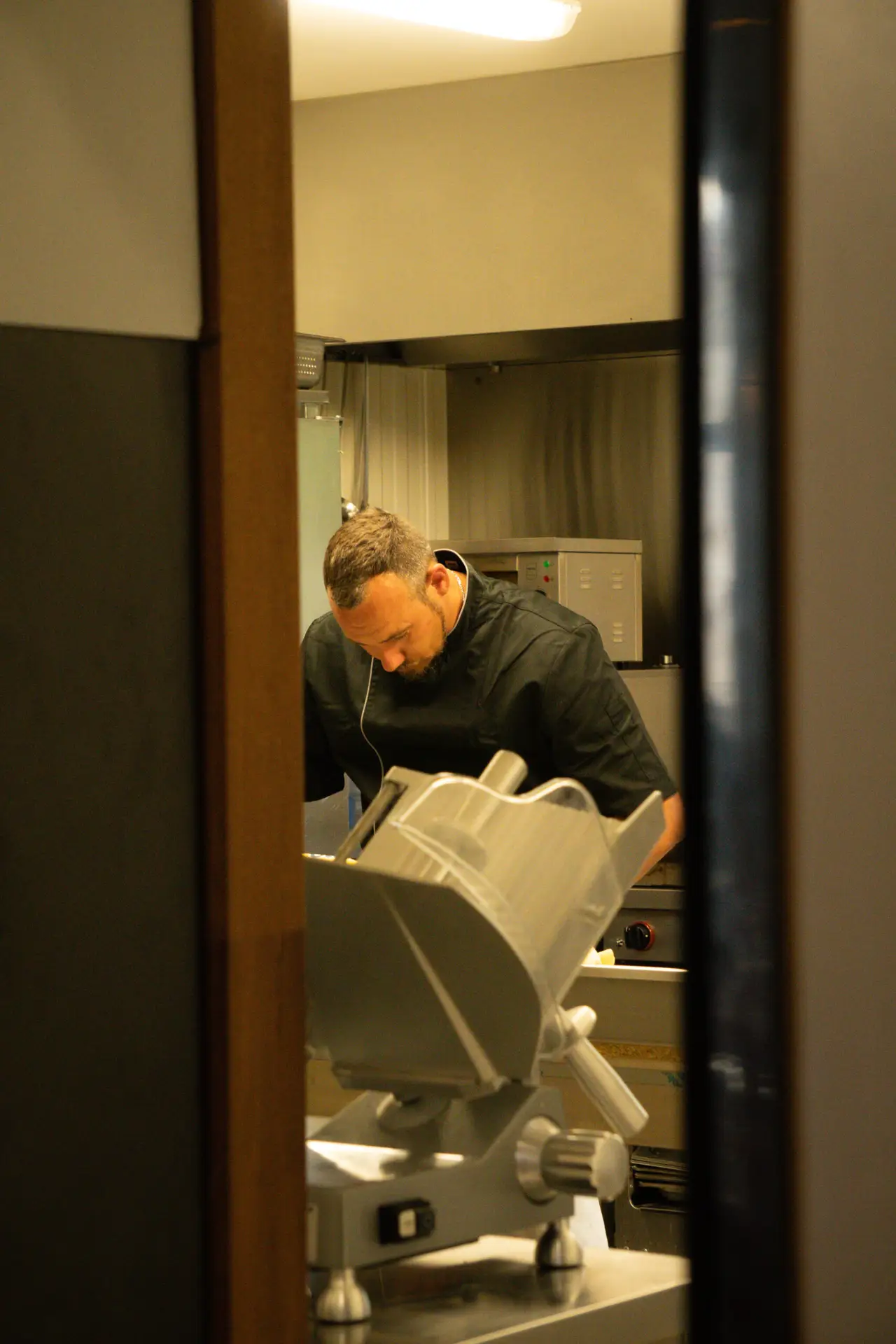Chef penché devant un four professionnel en cuisine, reportage behind-the-scenes par Aptitude Pro.